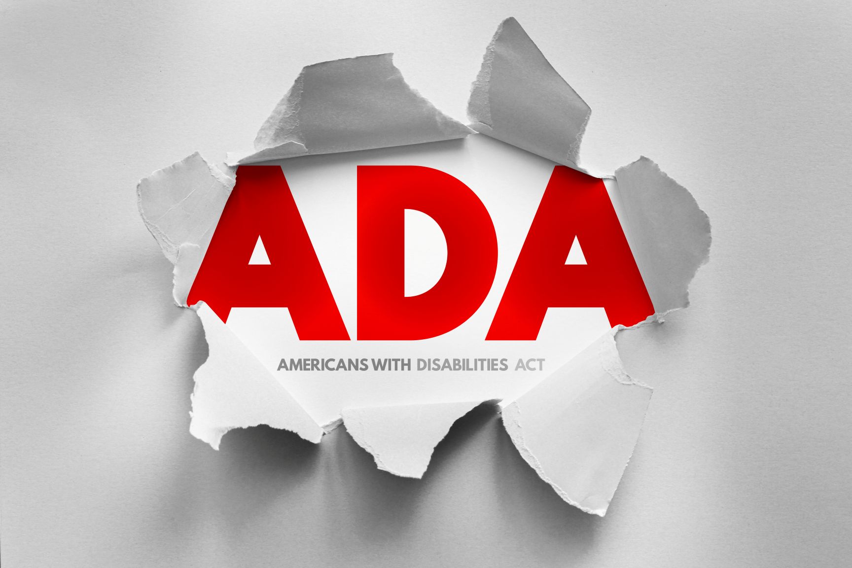ADA acronym, representing the Americans with Disabilities Act, in bold red letters revealed through torn paper.